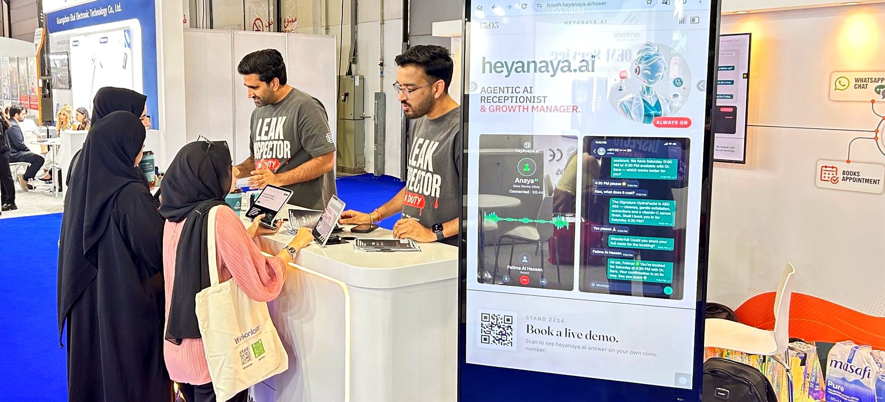Clinic visitors at the heyAnaya stand while Anaya books an appointment live on the screen beside them